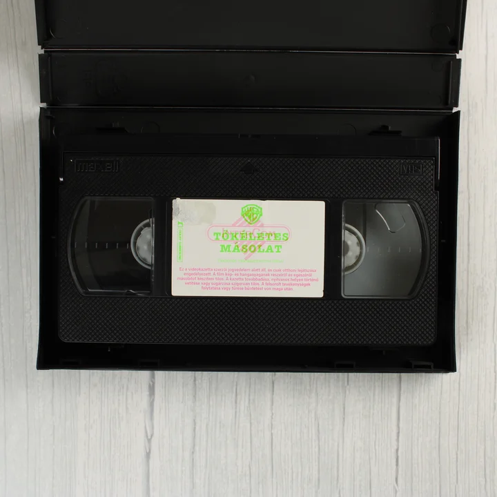 A nyitott tokban lévő Maxell VHS kazetta a Tökéletes másolat feliratú címkével
