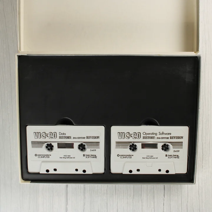 VIC-20 History szoftver kazetták Két fehér magnókazetta a fekete műanyag tartóban a dobozon belül.