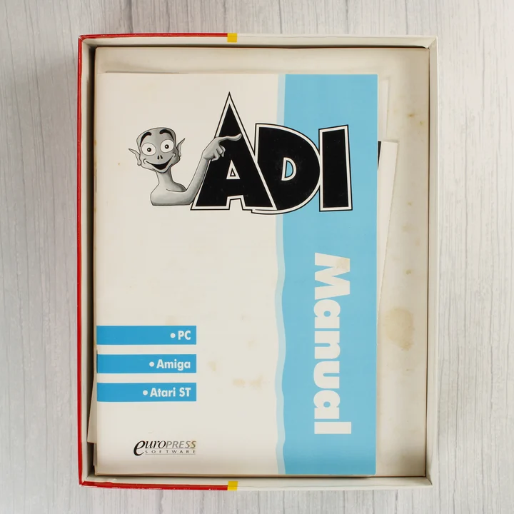 A nyitott doboz belseje a fehér ADI Manual kézikönyvvel.