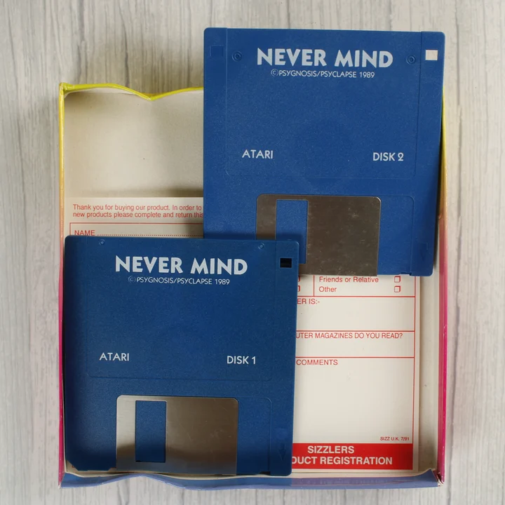Két kék floppy lemez és egy regisztrációs kártya a Never Mind játék dobozában.