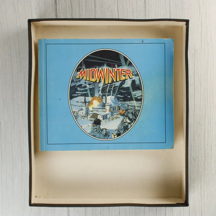 Midwinter kézikönyv A Midwinter játék kézikönyve a nyitott dobozban.