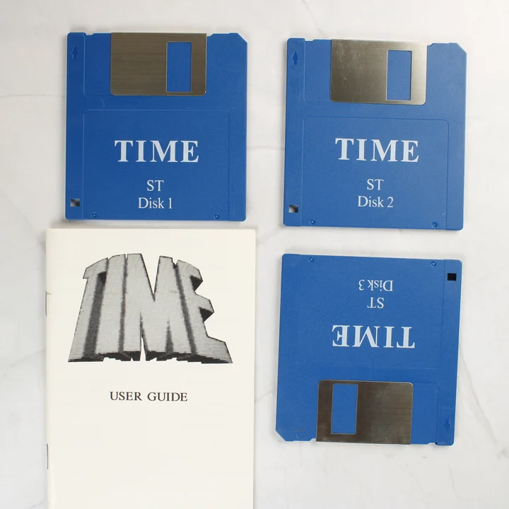 Három kék floppy lemez és egy fehér felhasználói kézikönyv a TIME videójátékhoz.