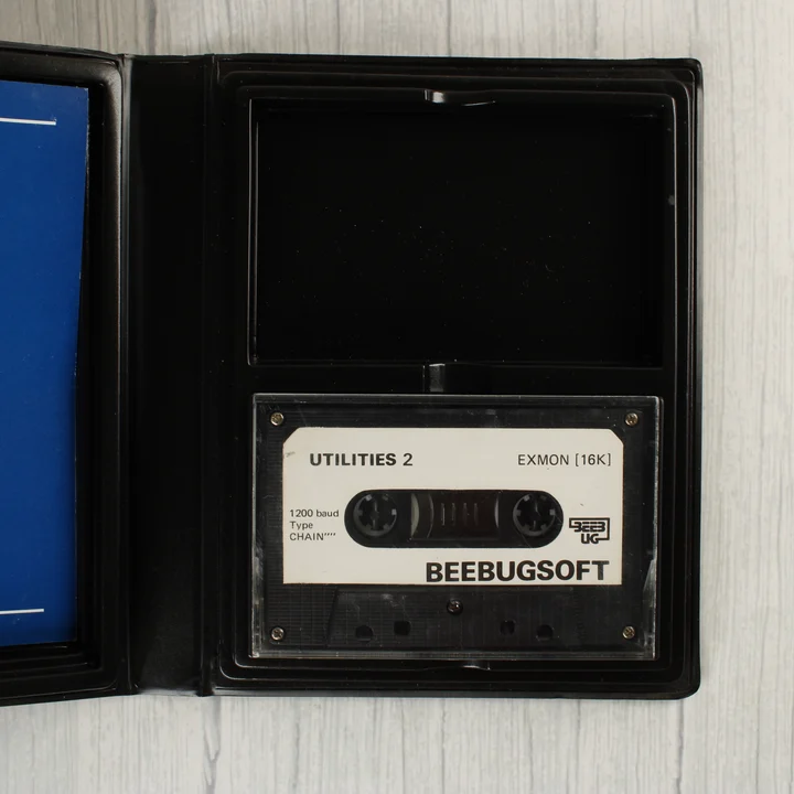 A nyitott tok belseje, amelyben egy fekete magnókazetta látható fehér címkével.