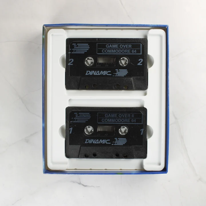 Game Over I és II kazetták Két fekete magnókazetta a Game Over videójátékokkal egy fehér tálcában