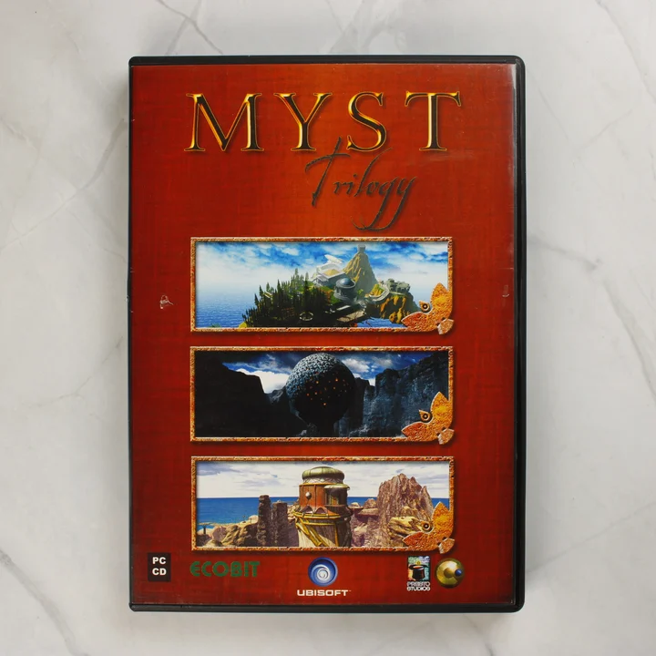 A Myst Trilogy PC-s videójáték előlapi borítója vörös háttérrel és három tájképpel.