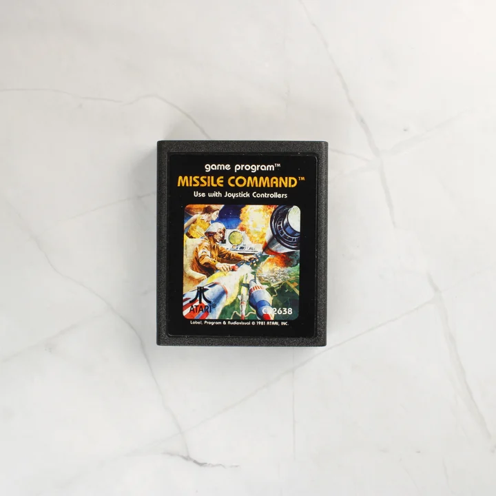 A Missile Command videójáték fekete cartridge-e színes illusztrált címkével.