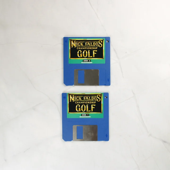 Nick Faldo's Championship Golf floppy lemezek Két kék Amiga floppy lemez a Nick Faldo's Championship Golf játékhoz