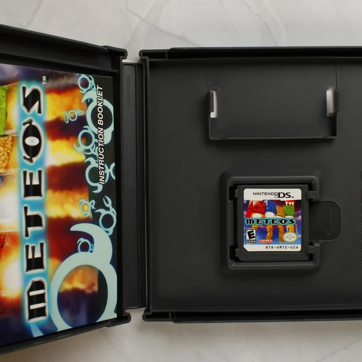 Nyitott Nintendo DS tok Meteos cartridge-dzsel és kiskönyvvel