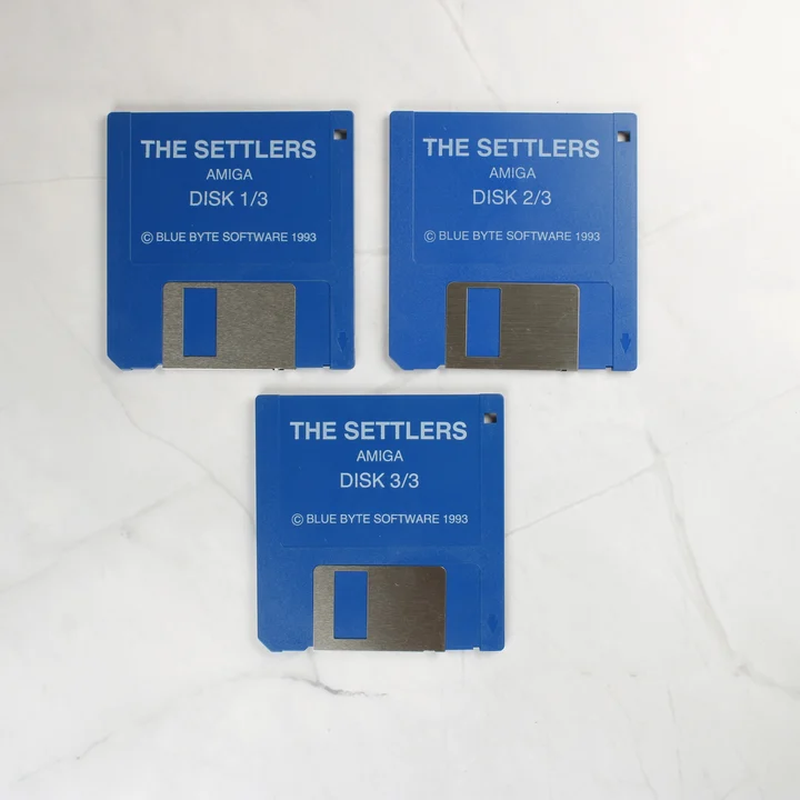 The Settlers Amiga floppy lemezek Három kék Amiga floppy lemez a The Settlers játékhoz