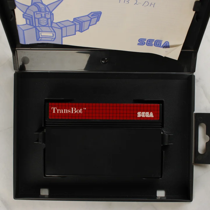 Nyitott TransBot játékdoboz a cartridge-dzsel és az útmutatóval