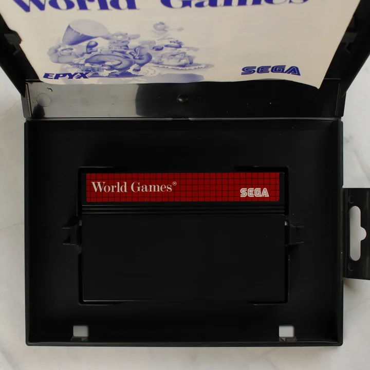 A nyitott tok belseje a World Games cartridge-dzsel és az útmutatóval.