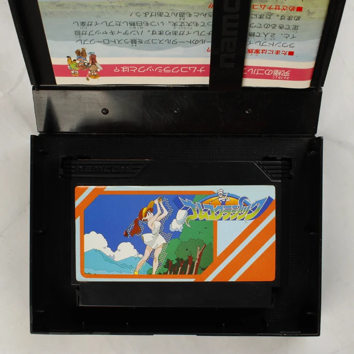 Nyitott Namco Classic játékdoboz a cartridge-dzsel és az útmutatóval