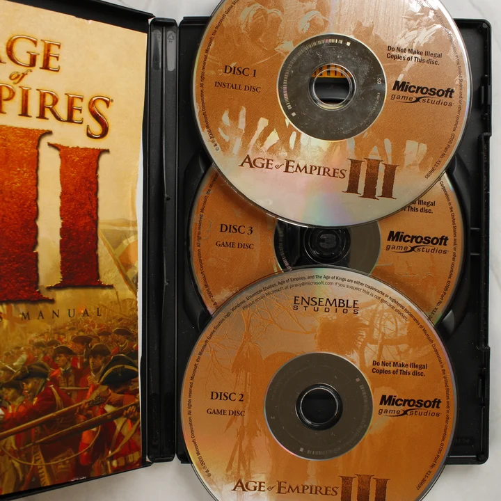 Age of Empires III lemezek és kézikönyv Nyitott tok az Age of Empires III három CD-jével és a kézikönyvvel