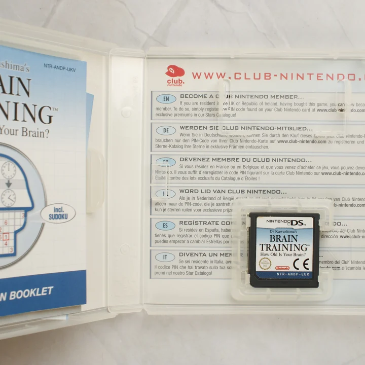 Nyitott Nintendo DS tok a Brain Training cartridge-dzsel és kézikönyvvel