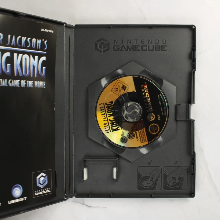 Nyitott Nintendo GameCube tok a King Kong játékkal és kézikönyvvel