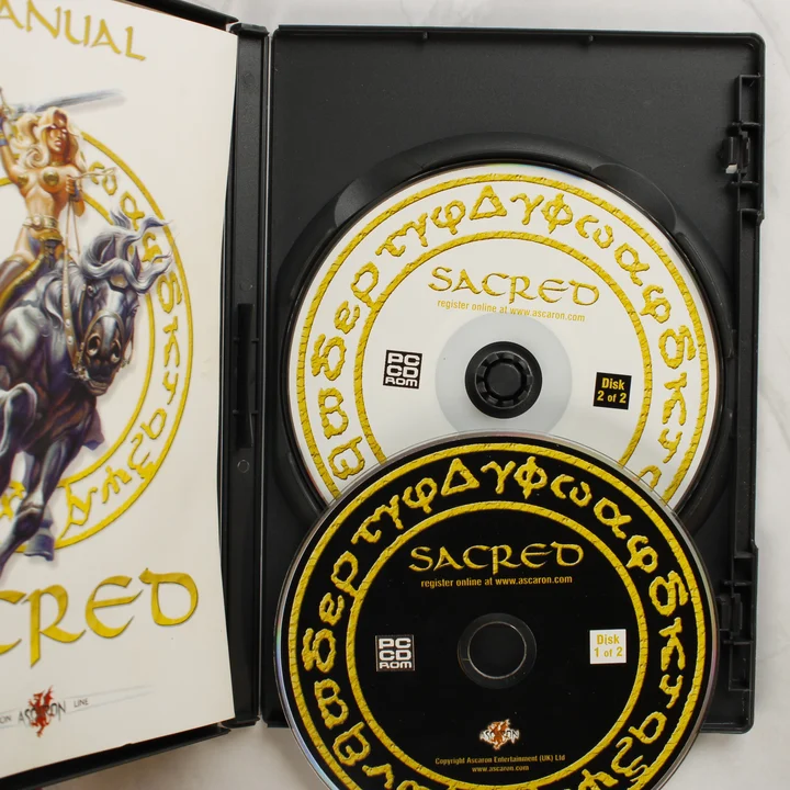 Sacred PC lemezek és kézikönyv A nyitott Sacred játéktok a két CD-vel és a kézikönyvvel