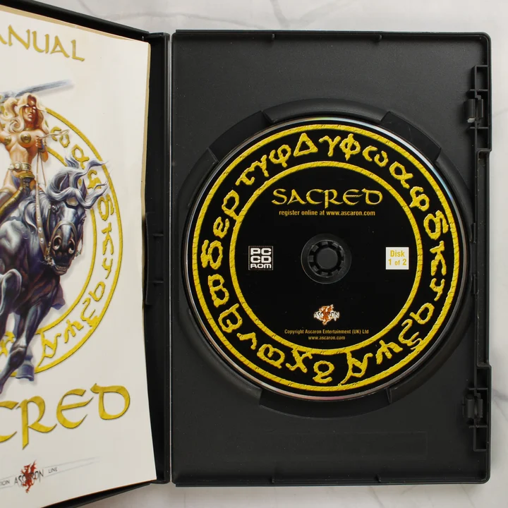 A Sacred videójáték nyitott tokja a lemezzel és a kézikönyvvel