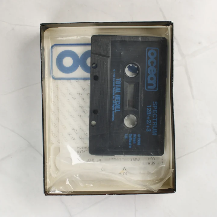 A Total Recall játék fekete kazettája a nyitott dobozban.