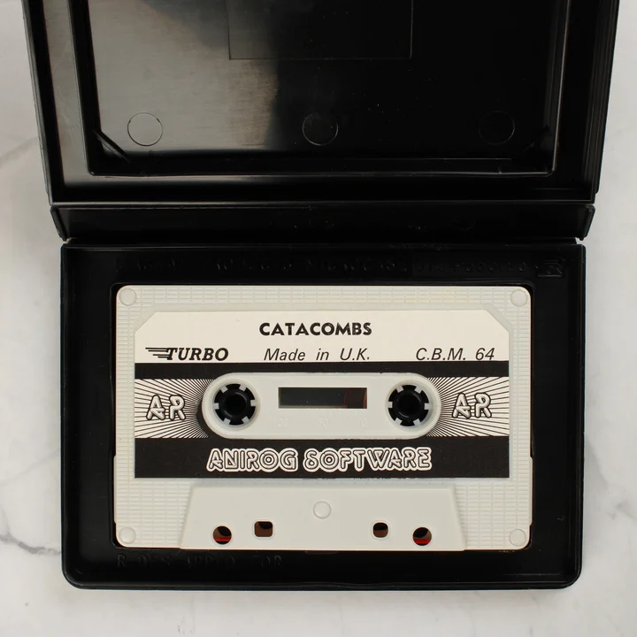 Catacombs C64 kazetta A Catacombs videójáték fehér magnókazettája a nyitott fekete tokban
