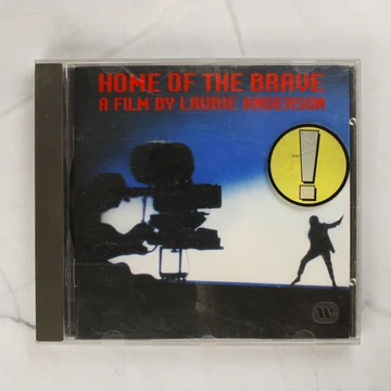 Laurie Anderson Home of the Brave CD előlapja sárga felkiáltójeles matricával