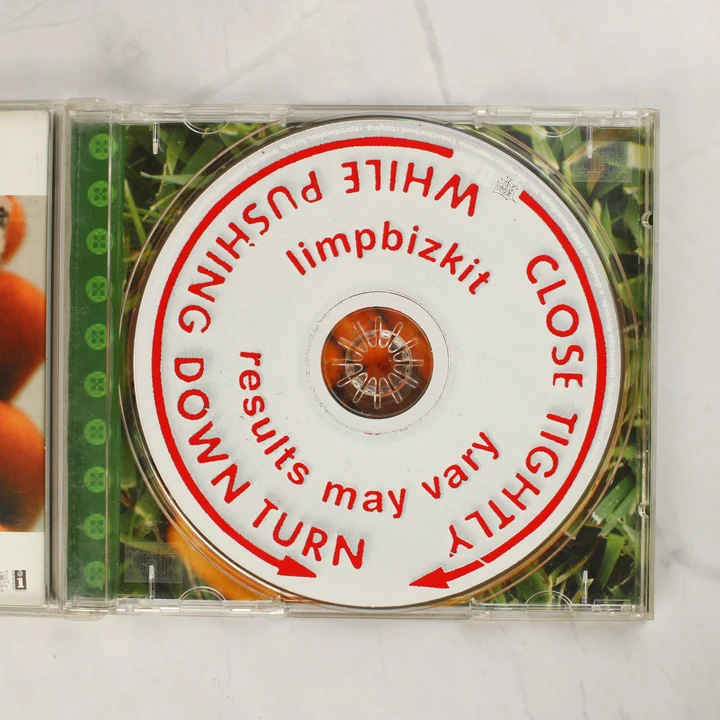 A nyitott CD-tokban lévő fehér színű Limp Bizkit Results May Vary CD lemez piros feliratokkal
