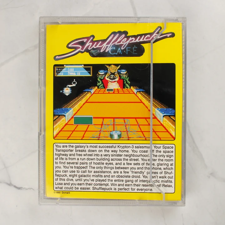 Shufflepuck Café Amiga játék tok hátlap A Shufflepuck Café Amiga videójáték tokjának hátoldala a sárga borítóval