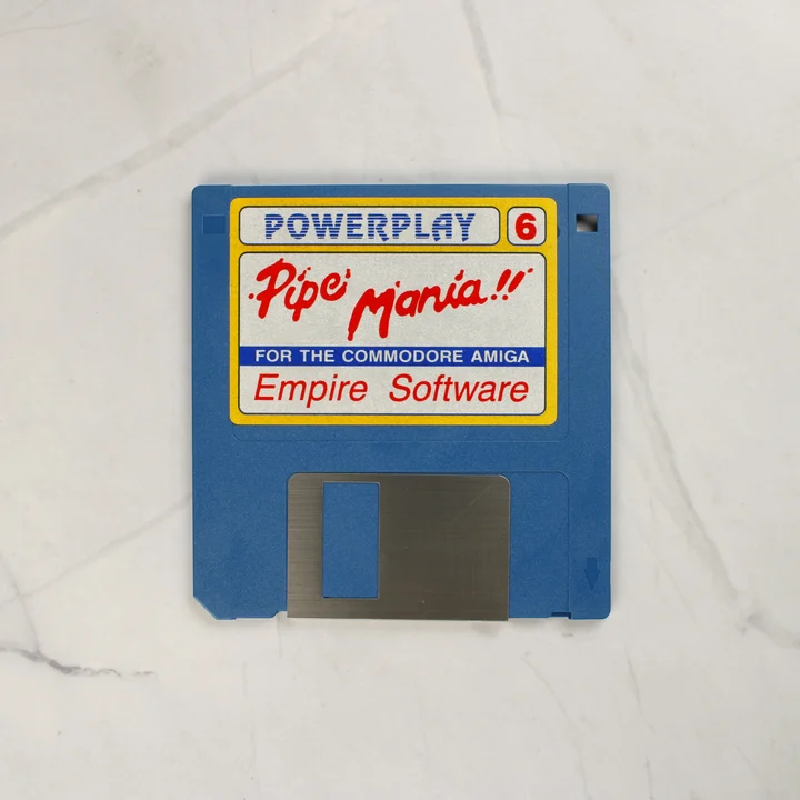 Kék színű 3,5 colos floppy lemez Pipe Mania címkével Commodore Amiga számítógéphez