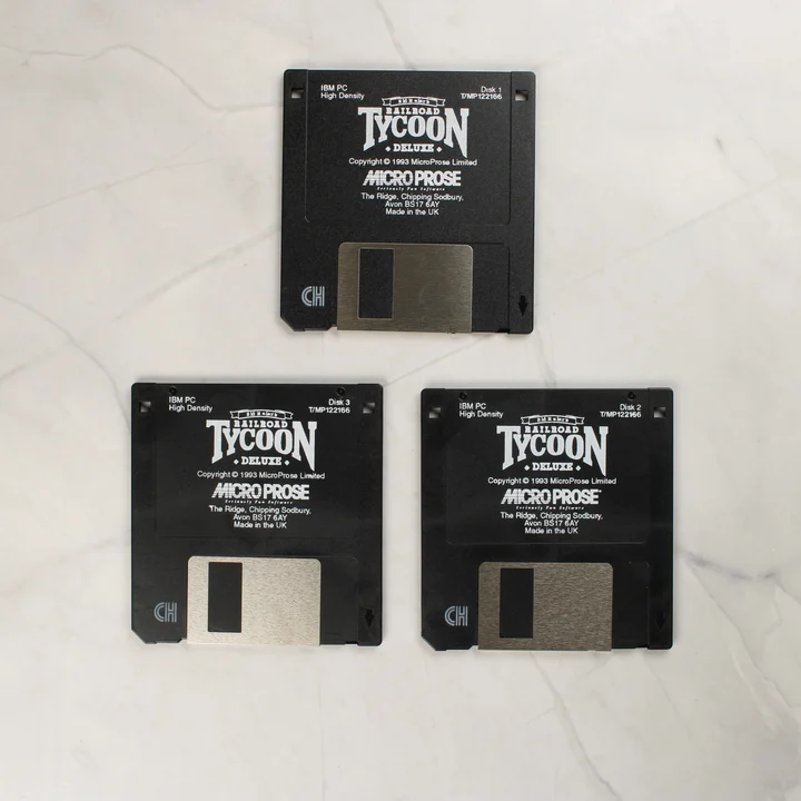 Három darab fekete, 3,5 colos Railroad Tycoon Deluxe floppy lemez egymás mellett