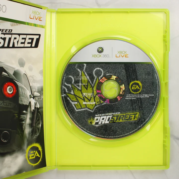 A nyitott Xbox 360 tok a Need for Speed ProStreet lemezzel és a kézikönyv szélével
