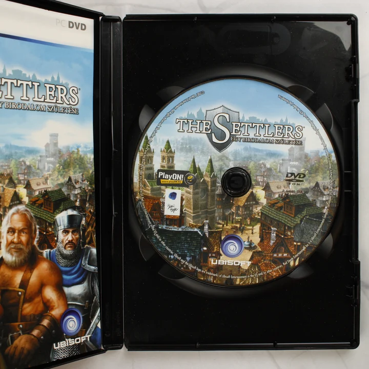 The Settlers: Egy birodalom születése PC lemez és belső The Settlers: Egy birodalom születése nyitott tokja a DVD-ROM lemezzel és a kézikönyvvel