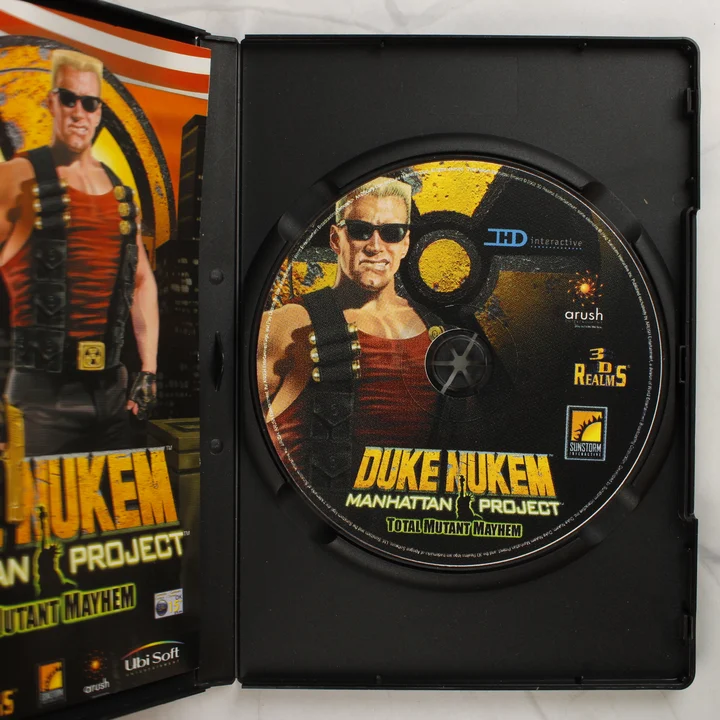 A nyitott tok a Duke Nukem: Manhattan Project CD-ROM lemezzel és a kézikönyvvel
