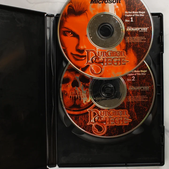 A Dungeon Siege játék két darab CD-lemeze a nyitott műanyag tokban