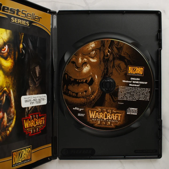 Warcraft III Reign of Chaos tok belseje lemezzel és CD-kulccsal Nyitott Warcraft III tok benne a CD-ROM lemezzel és a borítón lévő CD-kulccsal
