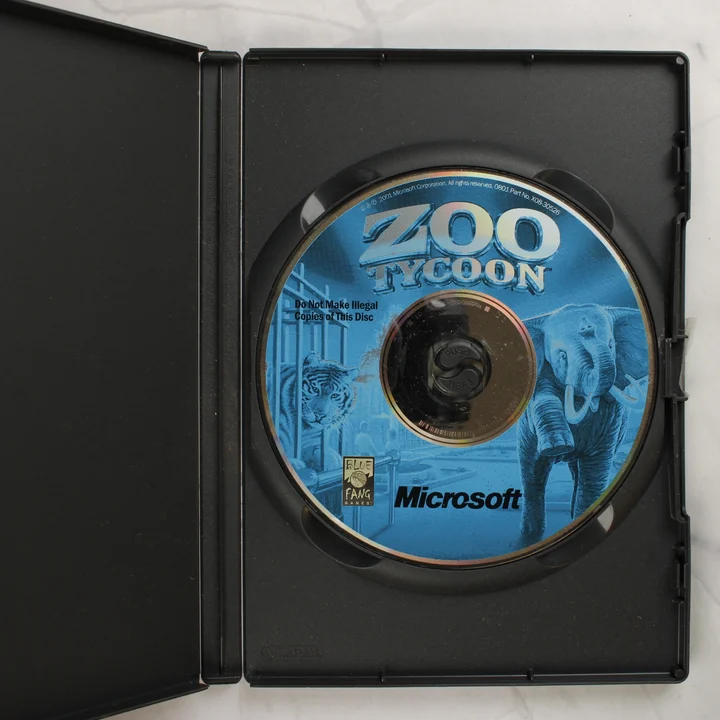 Zoo Tycoon CD-ROM a nyitott tokban Nyitott fekete műanyag tok a Zoo Tycoon CD-ROM lemezzel