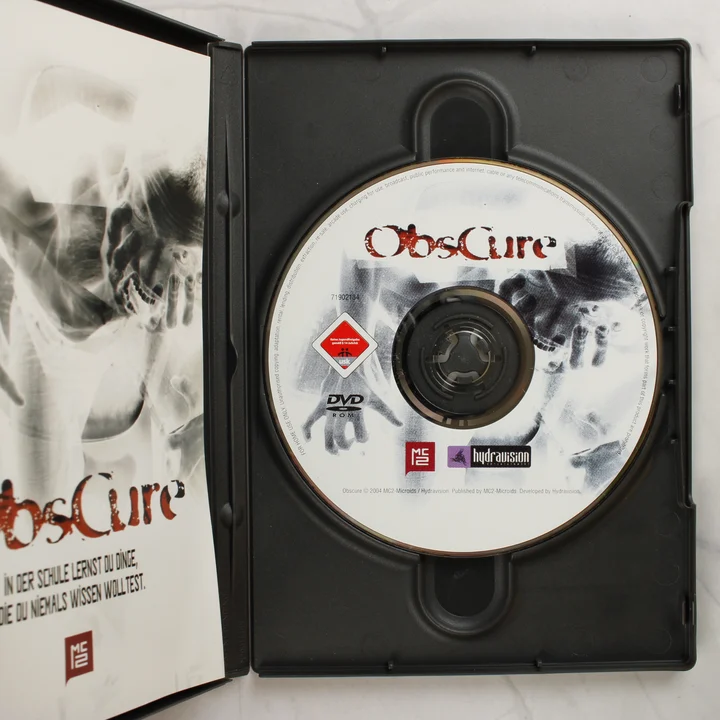Nyitott műanyag tok az Obscure DVD-ROM lemezzel és kézikönyvvel