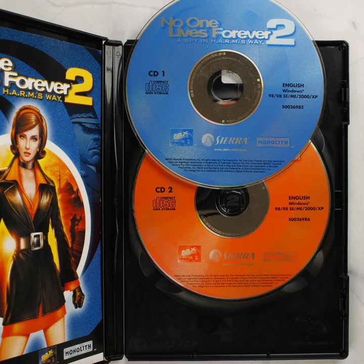 No One Lives Forever 2 kinyitott tokja a két CD-ROM lemezzel és a kézikönyvvel