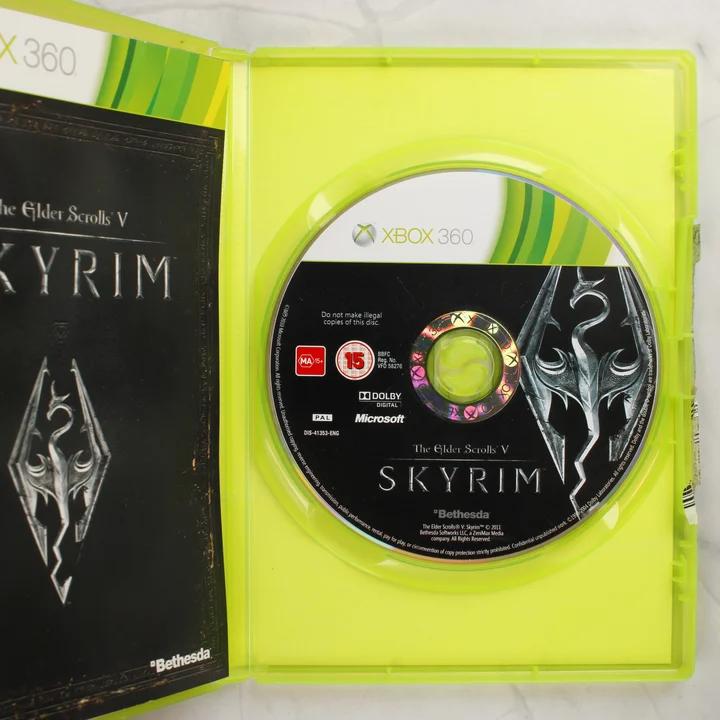 Nyitott Xbox 360 tok a Skyrim lemezzel és a füzettel