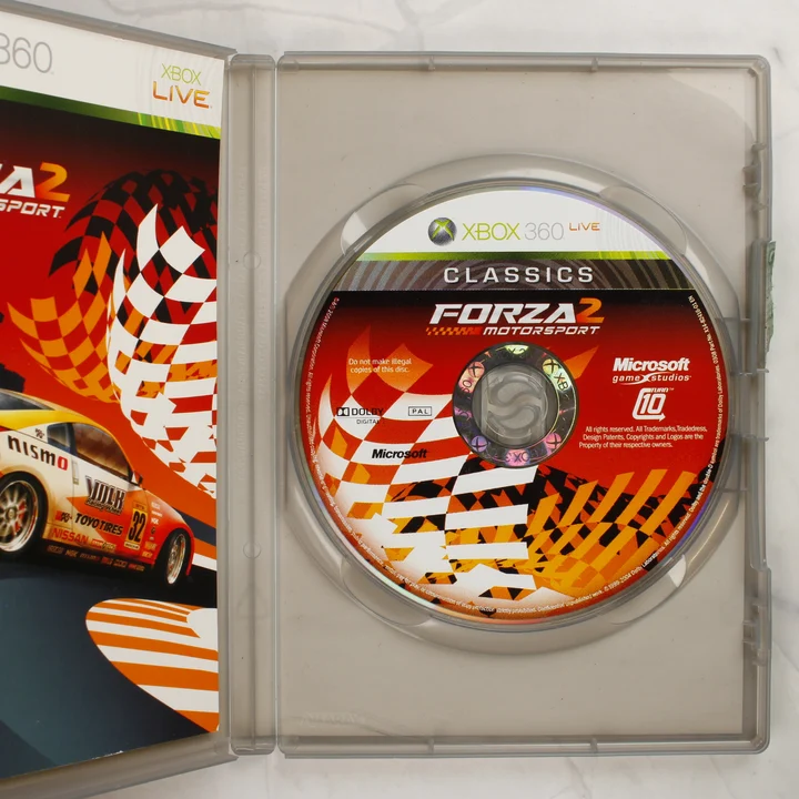 Nyitott Xbox 360 tok benne a Forza Motorsport 2 játéklemezzel és kézikönyvvel