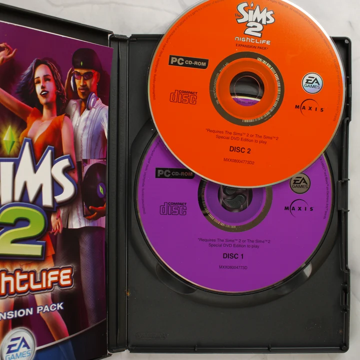 The Sims 2 Nightlife kinyitott tokja a két CD-ROM lemezzel és a kézikönyvvel