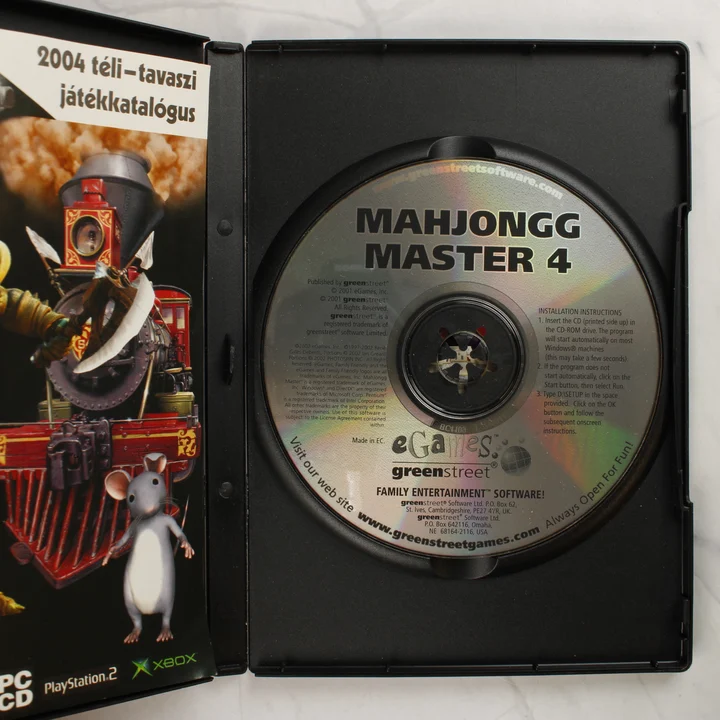 MahJongg Master 4 PC CD lemez és tok belső része A kinyitott műanyag tok a benne lévő CD-ROM lemezzel és a 2004-es játékkatalógussal