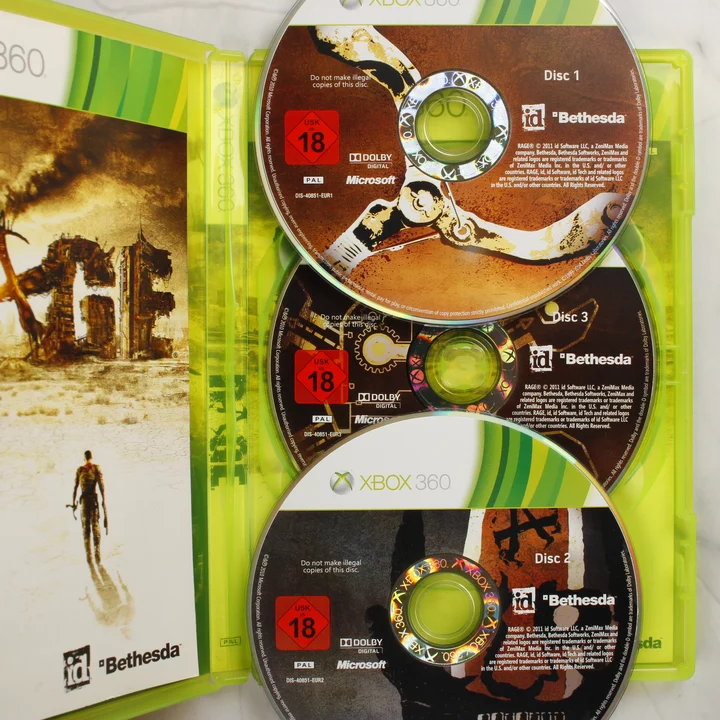 A nyitott Xbox 360 tok a RAGE játék három lemezével
