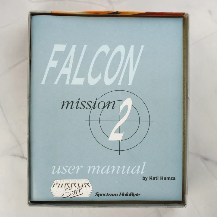 Falcon Mission Disk 2 kézikönyv a nyitott dobozban Falcon Mission Disk 2 Amiga kézikönyv a doboz belsejében