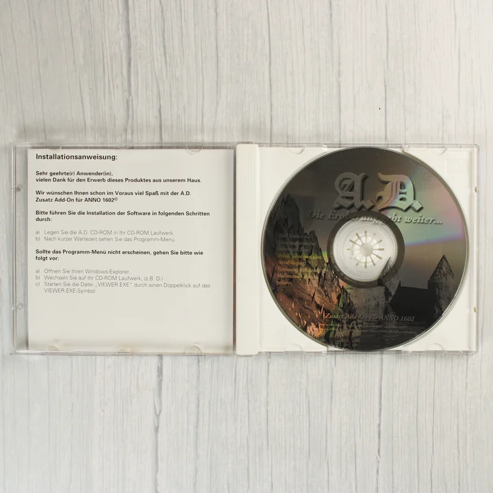 Nyitott CD-tok a szoftver lemezével és az útmutatóval