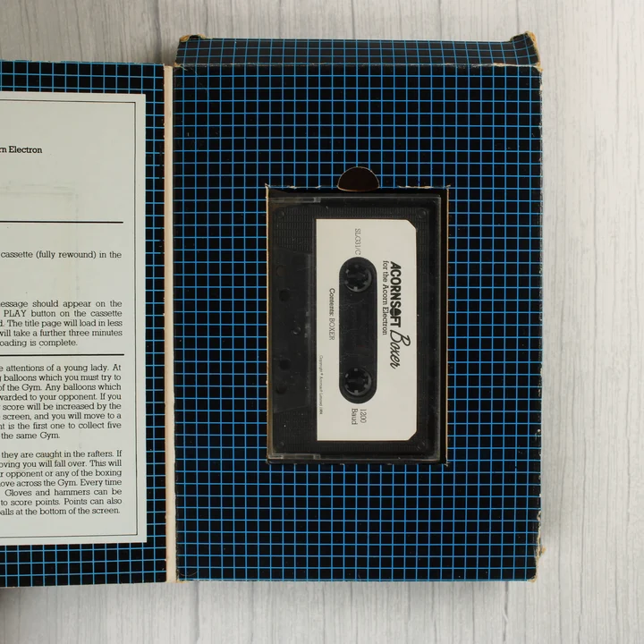 A nyitott doboz belseje a fekete kazettával és a használati útmutató részletével.